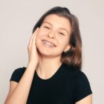 Chica sonriendo con brackets -¿Los aparatos de ortodoncia dañan tus dientes? - Clínica Bousoño Vargas